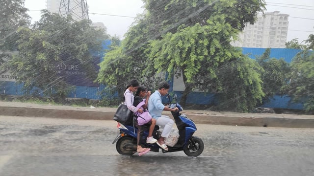 Commuters on their way near Noida sector-51 as heavy rain hits the National Capital Region. 