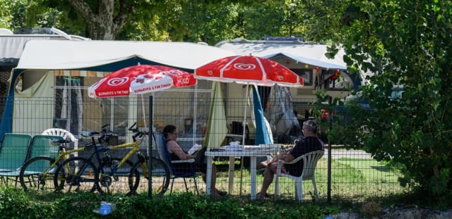 Des vacanciers assis à l'ombre dans un camping au Bourget-du-Lac, le 8 août 2025 en Savoie