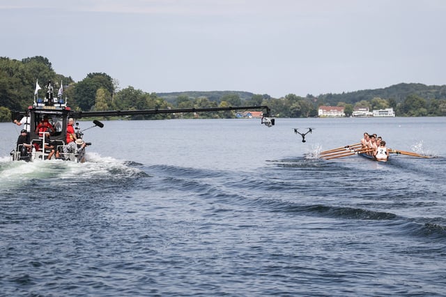 Ein Boot mit Kamerakran und eine Drohne verfolgen Schauspieler und professionelle Ruderer im Deutschland-Achter (r) bei Dreharbeiten auf dem Ratzeburger Küchensee