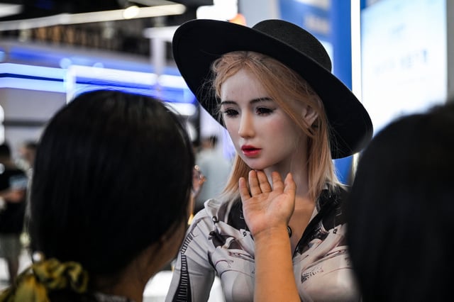 A woman touches a humanoid robot during the World Artificial Intelligence Conference at the Shanghai World Expo and Convention Center in Shanghai on July 28, 2025.