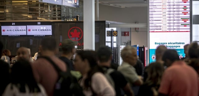 Des voyageurs consultent un panneau d'information sur les vols annulés d'Air Canada à l'aéroport Pierre-Elliott Trudeau à Montréal, au Québec, le 17 août 2025 au Canada