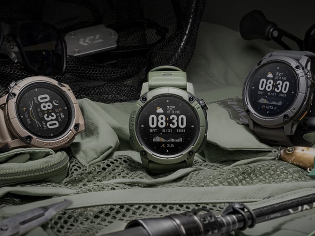 A photo of the green, grey, and brown COROS NOMAD watches sitting on a tent with camping equipment nearby.