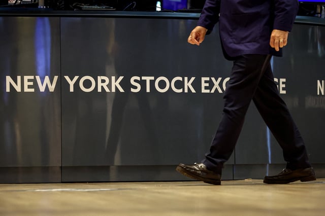 A trader walks past on the floor at the New York Stock Exchange (NYSE) in New York City, U.S., August 14, 2025.  REUTERS/Brendan McDermid/File Photo