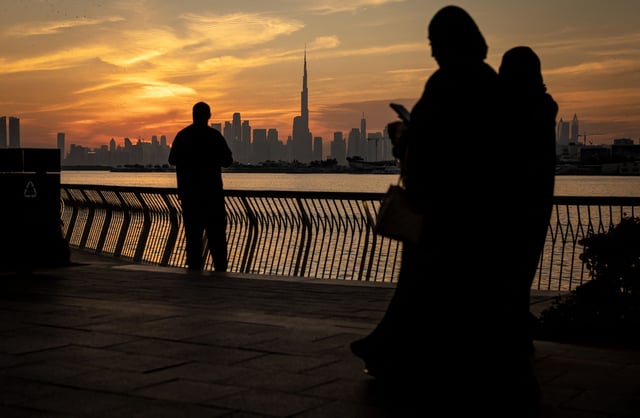 People walk on Creek Harbour as the Dubai skyline with Burj Khalifa, the world's largest building (C) is seen in the background on February 5, 2025.