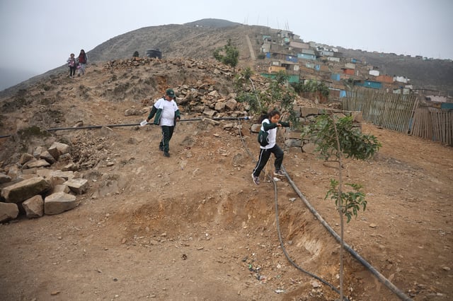 Escolares pasan junto a los escombros de un muro de 4,5 kilómetros, que separaba lujosas urbanizaciones de una comunidad vecina que vivía en la pobreza, mientras es derribado, en Lima, Perú. 31 de agosto de 2023. REUTERS/Sebastian Castaneda