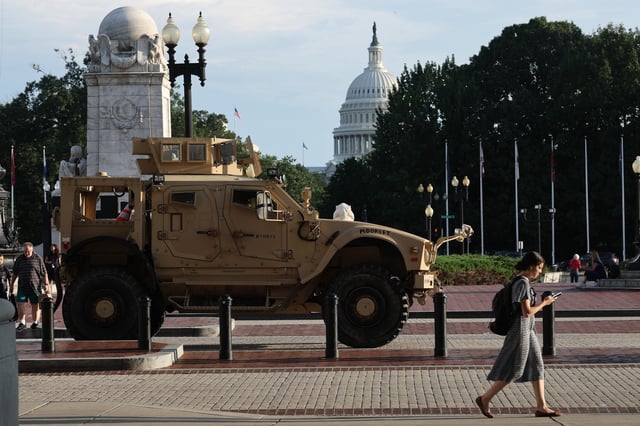 Pedestrians pass an MRAP (Mine Resistant Ambush Protected Vehicles) combat vehicle deployed by the Washington DC National Guard outside Union Station on August 14, 2025 in Washington, DC. (Photo by Win McNamee/Getty Images)
