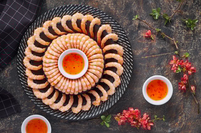 A stock photo of a shrimp platter displayed with sauce on a plate.