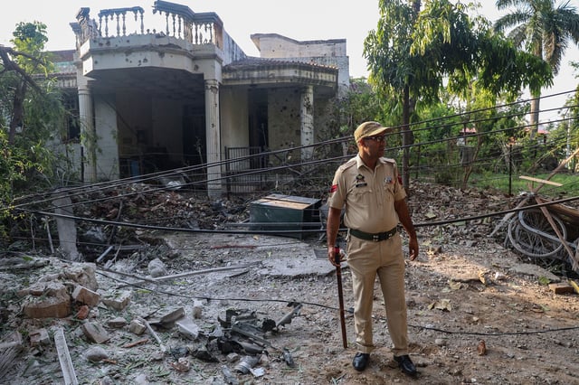 An Indian police officer stands outside a house that was damaged by overnight Pakistani artillery shelling in Jammu, India-administered Kashmir, on May 10.