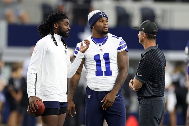 Micah Parsons #11 and Trevon Diggs #7 of the Dallas Cowboys speak with head coach John Harbaugh of the Baltimore Ravens prior to the NFL Preseason 2025 game at AT&amp;T Stadium on August 16, 2025 in Arlington, Texas.
