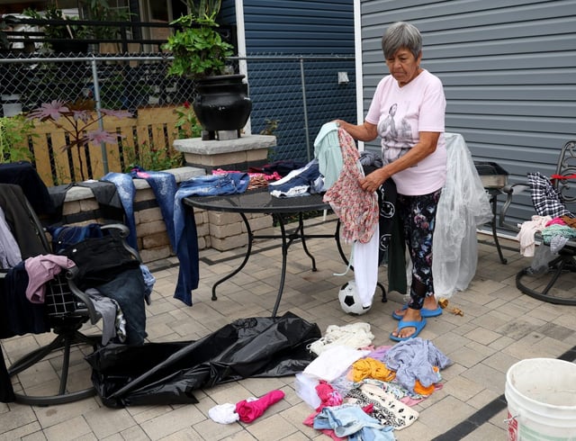 Maria Hernandez, whose basement flooded following two days of heavy rain, sorts through wet and soiled clothing in the 5600 block of South Fairfield Avenue in Chicago on Aug. 19, 2025. (Antonio Perez/Chicago Tribune)