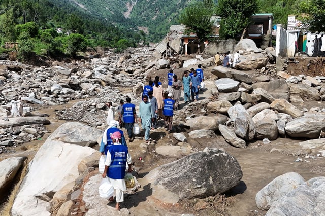 In this aerial picture, volunteers carry aid for residents, after flash floods hit Buner district in northern Pakistan's mountainous Khyber Pakhtunkhwa province on August 18, 2025.