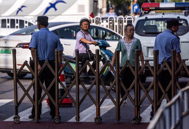 Police officers stand guard next to barriers blocking the street ahead of a rehearsal for a military parade, which marks the 80th anniversary of the end of World War Two, in Beijing, China August 16, 2025. REUTERS/Maxim Shemetov