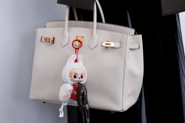 A Labubu toy hangs from a bidder's Hermes bag at an auction by Yongle International Auction in Beijing, China June 10, 2025. REUTERS/Tingshu Wang/ File Photo