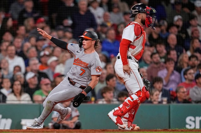 Baltimore Orioles’ Jackson Holliday, left, runs past Boston Red Sox catcher Connor Wong while scoring on a single by Ryan Mountcastle in the fifth inning of a baseball game at Fenway Park, Tuesday, Aug. 19, 2025, in Boston. (AP Photo/Charles Krupa)