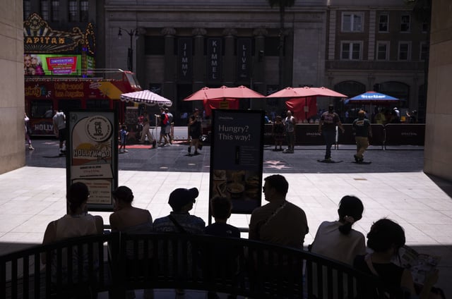 Tourists rest in the shade in the Hollywood section of Los Angeles, Tuesday, Aug. 19, 2025. (AP Photo/Jae C. Hong)