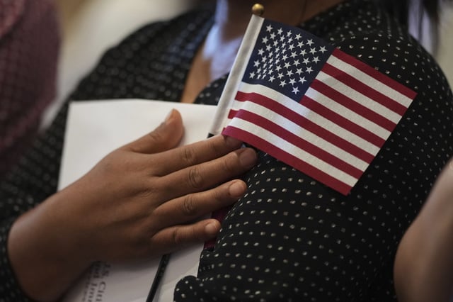 A woman clutches a US flag as she and applicants from other countries prepare to take the oath of citizenship in commemoration of Independence Day during a Naturalization Ceremony in San Antonio, July 3, 2025.