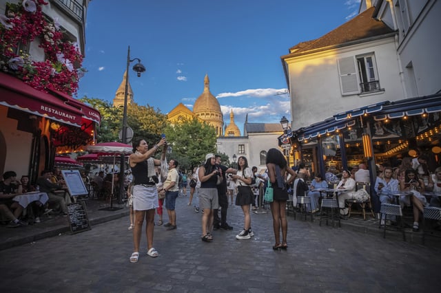 Tourists stroll in the Montmartre district in Paris, France, Monday, Aug. 4, 2025. (AP Photo/Aurelien Morissard)