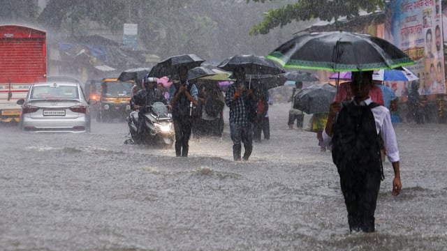 Mumbai: Commuters make way through a waterlogged road amid rainfall, in Mumbai, Tuesday, Aug. 19, 2025. (PTI Photo)(PTI08_19_2025_000449B)
