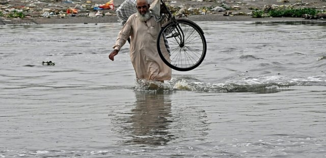 Un homme traverse une rue inondée de Karachi, mégapole du Pakistan où les pluies de mousson ont fait plus de 400 morts en une semaine, le 20 août 2025
