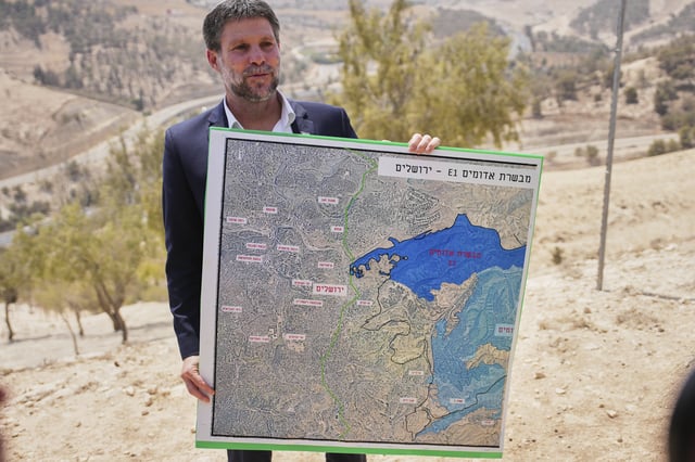 CORRECTS DAY Israeli Finance Minister Bezalel Smotrich holds a map that shows the E1 settlement project during a press conference near the settlement of Maale Adumim, in the Israeli-occupied West Bank, Thursday, Aug. 14, 2025. (AP Photo/Ohad Zwigenberg)
