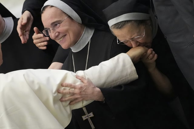 A nun kisses the hand of Pope Leo XIV during his weekly general audience, at The Vatican, Wednesday, Aug.20, 2025. (AP Photo/Gregorio Borgia)