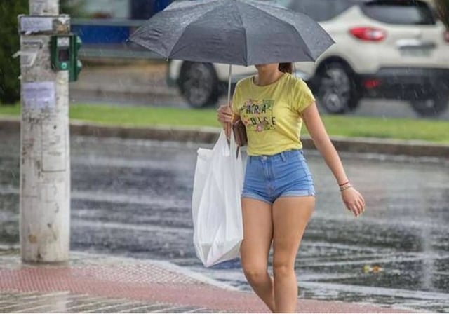 Una mujer camina con paraguas durante una tarde de verano con lluvias en Almería