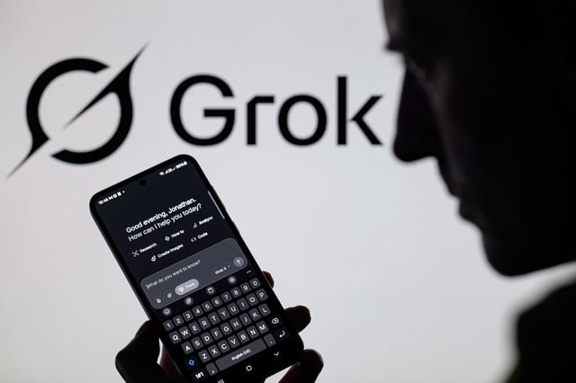 The Grok X AI app is used on a mobile phone with the Grok logo visible in the background in this photo illustration in Brussels, Belgium, on March 8, 2025. (Photo illustration by Jonathan Raa/NurPhoto)