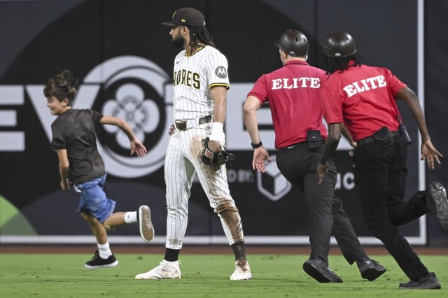 San Diego Padres right fielder Fernando Tatis Jr. looks on as security guards chase a young fan running on the field during the eighth inning of a game against the San Francisco Giants at Petco Park.