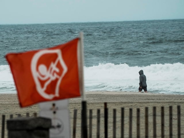 A person walks near the sea during Hurricane Erin, the first hurricane of the 2025 Atlantic season, on a beach in Avon-by-the Sea, New Jersey, U.S., August 20, 2025. REUTERS/Eduardo Munoz