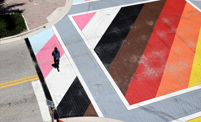 A pedestrian crosses the LGBTQ+ pride intersection of Northeast First Street and Northeast Second Avenue in Delray Beach on Monday, Aug. 18, 2025. (Carline Jean/South Florida Sun Sentinel)