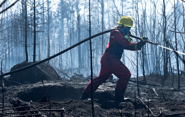 Rebekah Deveau, of the Annapolis Royal Volunteer Fire Department, sprays a burnt out area surrounding a communications tower.