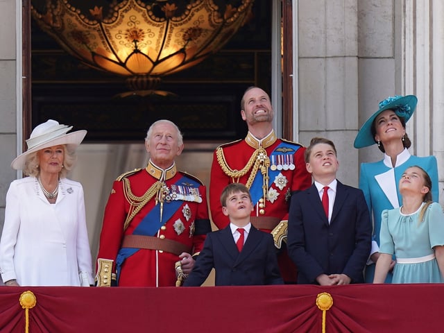 From the left, Britain's Queen Camilla, King Charles III, Prince Louis, Prince William, Prince George, Kate, Princess of Wales and Princess Charlotte, look up as they watch the flypast by the Red Arrows from the balcony of Buckingham Palace during the Trooping the Colour in London, Saturday, June 14, 2025. (AP Photo/Alberto Pezzali)