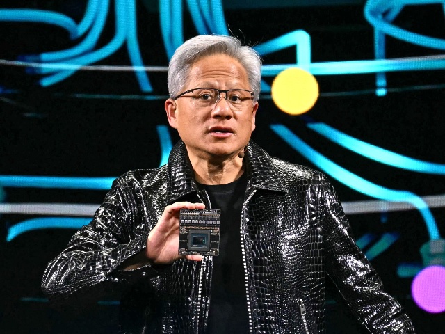 Nvidia CEO Jensen Huang holds a Nvidia's Drive Thor processor as he delivers a keynote address at the Consumer Electronics Show (CES) in Las Vegas, Nevada on January 6, 2025. Gadgets, robots and vehicles imbued with artificial intelligence will once again vie for attention at the Consumer Electronics Show, as vendors behind the scenes will seek ways to deal with tariffs threatened by US President-elect Donald Trump. The annual Consumer Electronics Show (CES) opens formally in Las Vegas on January 7, 2025, but preceding days are packed with product announcements. (Photo by Patrick T. Fallon / AFP)