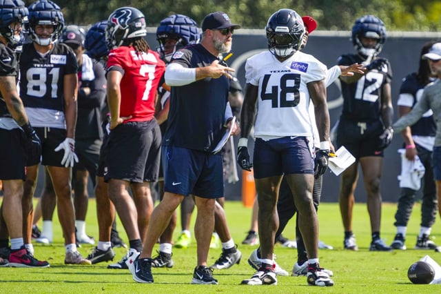 Houston Texans defensive coordinator Matt Burke, left, works with linebacker Christian Harris (48) during an NFL training camp practice at Houston Methodist Training Center in Houston, Wednesday, Aug. 20, 2025.