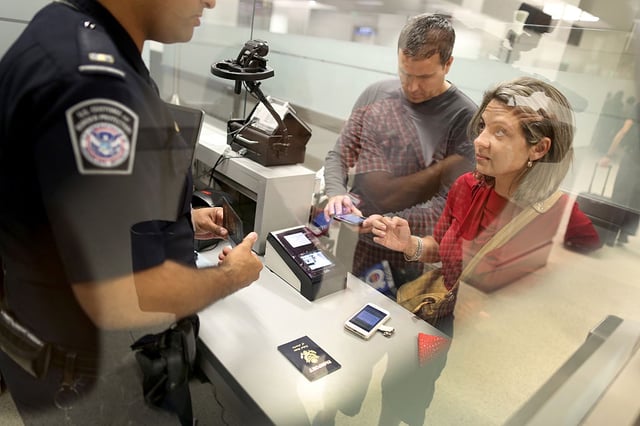 MIAMI, FL - MARCH 04: Leonel Cordova (L) and Noris Cordova speak to a CBP officer as they try to use their new mobile app at an entry point as the program is unveiled for international travelers arriving at Miami International Airport on March 4, 2015 in Miami, Florida. Miami-Dade Aviation Department and U.S. Customs and Border Protection (CBP) unveiled a new mobile app for expedited passport and customs screening. The app for iOS and Android devices allows U.S. citizens and some Canadian citizens to enter and submit their passport and customs declaration information using their smartphone or tablet and to help avoid the long waits in the exit lanes. (Photo by Joe Raedle/Getty Images)