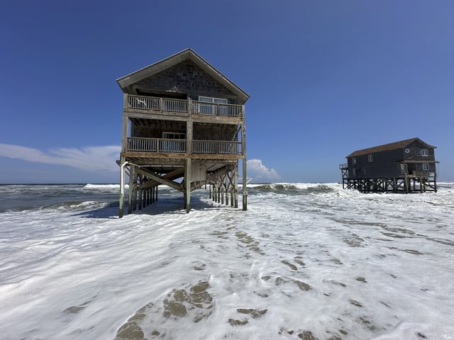 Two houses sit out in the heavy surf as Hurricane Erin passes offshore at Rodanthe, N.C., on Tuesday, Aug. 19, 2025. (AP Photo/Allen G. Breed)