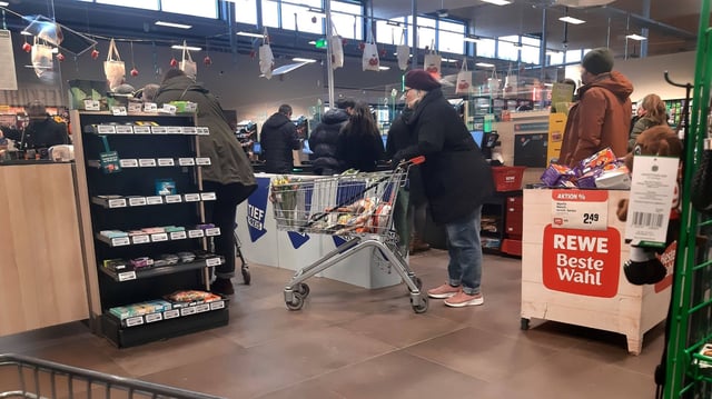Rewe-Kunden stehen an der Kasse (Symbolbild).