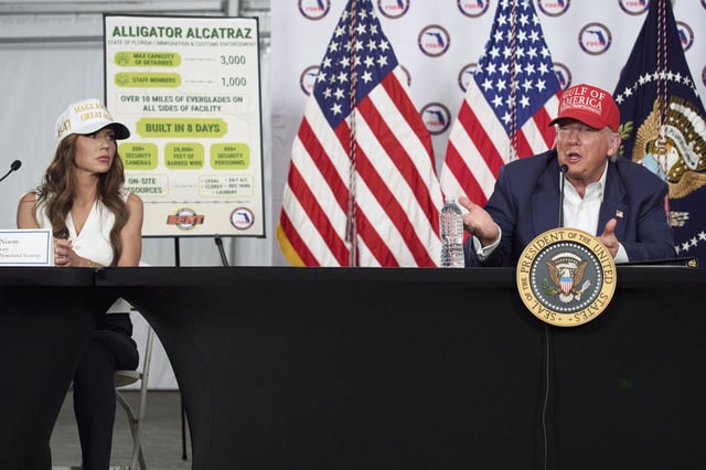 Homeland Security Secretary Kristi Noem listens as President Donald Trump speaks during a roundtable at "Alligator Alcatraz," a new migrant detention facility at Dade-Collier Training and Transition facility, Tuesday, July 1, 2025, in Ochopee, Fla.