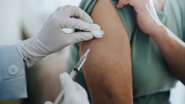 Close up of senior Asian woman getting Covid-19 vaccine in arm for Coronavirus immunization by a doctor at hospital. Elderly healthcare and illness prevention concept - stock photo