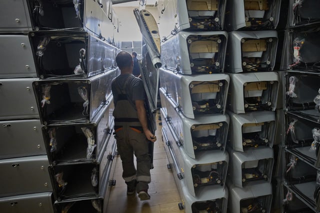 A worker carries part of a combat drone at Fire Point's secret factory in Ukraine on Thursday, Aug. 14, 2025. (AP Photo/Efrem Lukatsky)