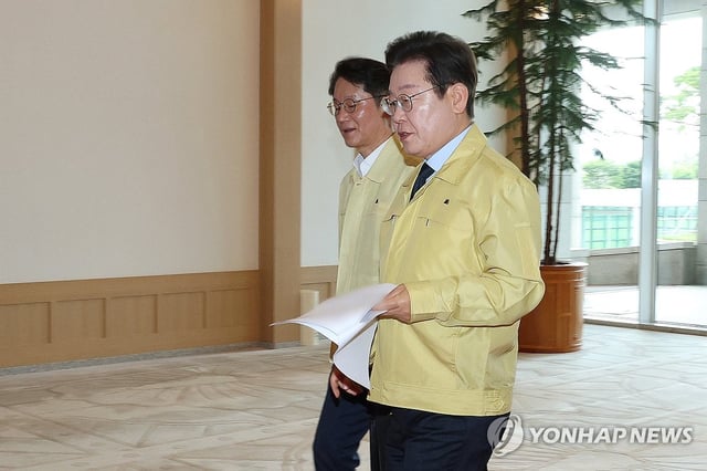 President Lee Jae Myung (front), clad in a civil defense suit, arrives at the presidential office in Seoul on Aug. 21, 2025. (Pool photo) (Yonhap)