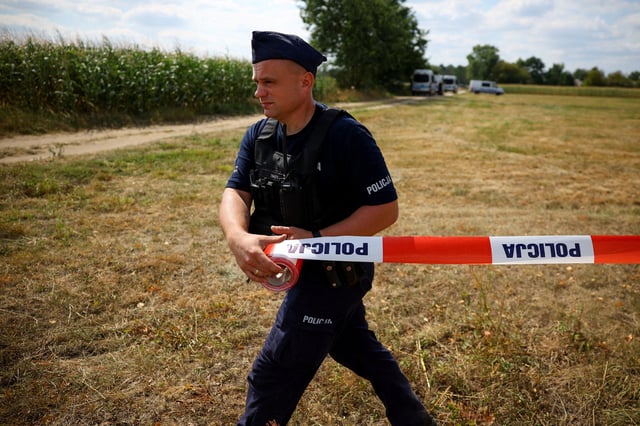 A police officer sets up a police tape, after an unidentified object fell and exploded in a cornfield overnight, according to Polish authorities, in the village of Osiny, eastern Poland. REUTERS/Kacper Pempel