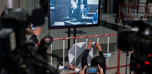 Des membres des médias devant un écran montrant la Première ministre thaïlandaise suspendue Paetongtarn Shinawatra lors d'une procédure devant la Cour constitutionnelle de Bangkok, le 21 août 2025