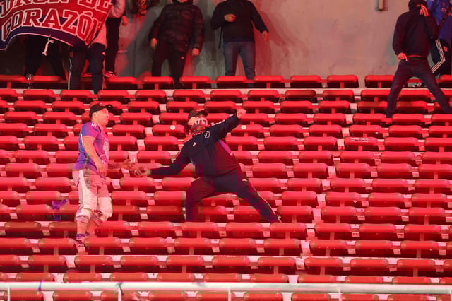 Spielabbruch nach Ausschreitungen: Ein Vermummter wirft einen Stein im Stadion