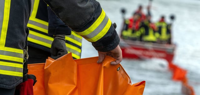 Eine Ölsperre wird aufs Wasser gezogen. So wie auf diesem Symbolbild kämpft aktuell auch die Hamburger Feuerwehr im Hafen gegen die Ausbreitung einer Ölschicht