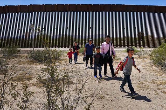 FILE - A family of five claiming to be from Guatemala and a man stating he was from Peru, in pink shirt, walk through the desert after crossing the border wall in the Tucson Sector of the U.S.-Mexico border, Aug. 29, 2023, in Organ Pipe Cactus National Monument near Lukeville, Ariz. (AP Photo/Matt York, File)