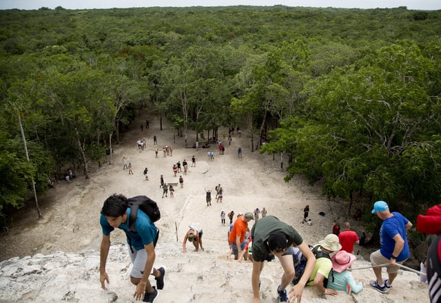 FILE - Tourists climb a Mayan temple at the archeological site of Coba, in Mexico's Yucatan Peninsula, Aug. 1, 2018. (AP Photo/Eduardo Verdugo, File)