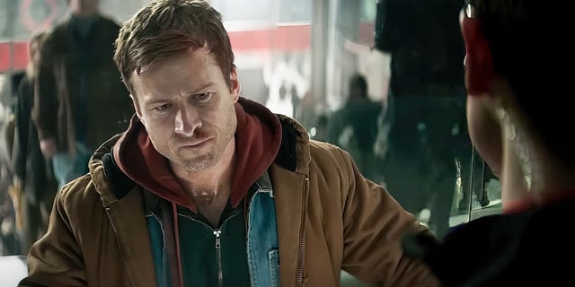 Glen Powell as Ben Richards looking frustrated as he stands in front of a glass window in The Running Man.