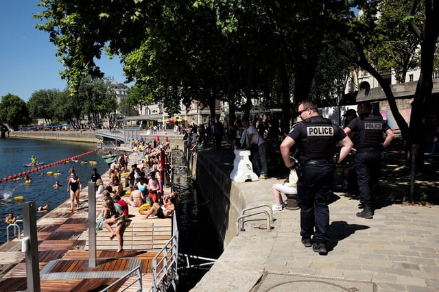 PARIS, FRANCE - AUGUST 17: People and tourists swim and sunbath at the Bras Marie safe bathing site on the river Seine under police surveillance in Paris on August 17, 2025. on August 17, 2025 in Paris, France. Earlier this summer Paris Mayor Anne Hidalgo launched three bathing sites across the city, marking the first season of public swimming in the River Seine in just over a hundred years. Hidalgo had made it a promise of her time in office to make the Seine swimmable again ahead of the 2024 Summer Olympics in Paris, with the city investing 1.4 billion euros in a clean-up project. Swimming in the Seine had been banned since 1923, due to the dangers of boat traffic and poor water quality. The new bathing areas offer changing areas and will be monitored by life guards for the swimming season, from July 5 to August 31. (Photo by Antoine Gyori - Corbis/Corbis via Getty Images)