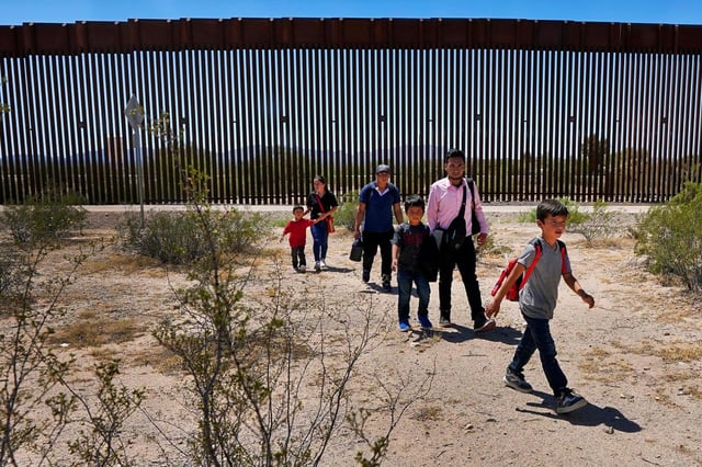 ARCHIVO - Una familia de cinco personas que dice ser de Guatemala y un hombre que dice ser de Perú, con camisa rosa, caminan por el desierto después de cruzar el muro fronterizo en el sector de Tucson de la frontera entre EEUU y México, el 29 de agosto de 2023, cerca de Lukeville, Arizona. (AP Foto/Matt York, Archivo)
